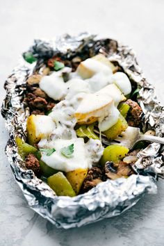 an aluminum foil container filled with food on top of a white countertop and covered in tinfoil