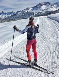 a woman on skis in the snow with mountains in the backgrouund