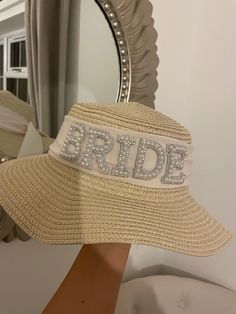 a bridal hat with the word bride on it is held up in front of a mirror