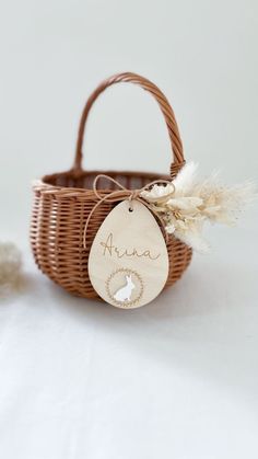 a small basket with a wooden name tag attached to it, sitting on a white surface