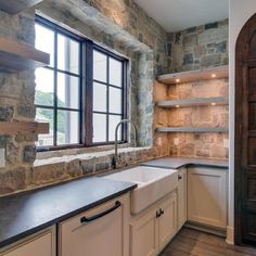 an empty kitchen with stone walls and cabinets