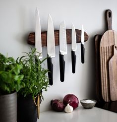 five knives are hanging on the wall next to some vegetables