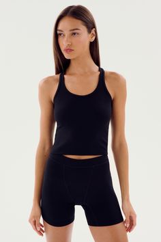 A person with long hair wearing an Ashby Rib Crop - Black by SPLITS59 and black shorts, perfect for gym workouts, stands against a plain white background. Barre Pilates, Running Yoga, Spin Class, Rib Fabric, Layering Tanks, Soft Baby, Hug You, Ribbed Fabric, Baby Soft