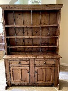 an old wooden hutch with two doors and drawers on the front, sitting in a room