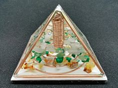 a triangle shaped glass object with green and white beads