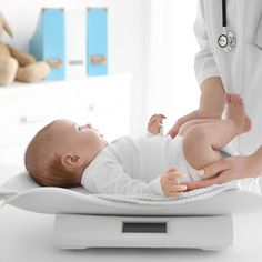 a baby laying on top of a scale being held by a doctor's hand