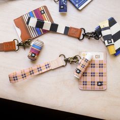 several keychains are laid out on a table with tags attached to them and one has a cell phone in it