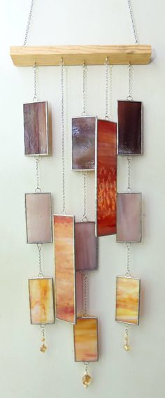 a wall hanging made out of different colored glass tiles and metal chains on a white wall