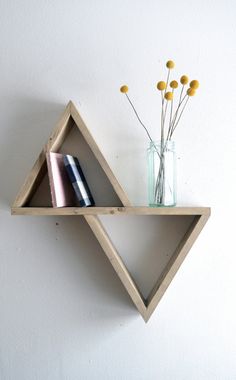 two wooden shelves with vases and flowers on each shelf in front of a white wall