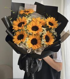 a bouquet of sunflowers is wrapped in black paper