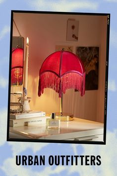 a red lamp sitting on top of a table next to a white book and candle