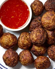 some meatballs are on a plate next to a small bowl of ketchup