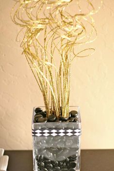 a vase filled with rocks and plants on top of a table