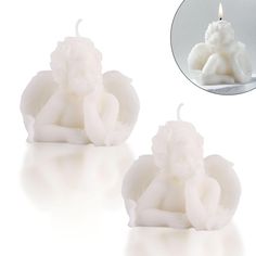 two white candles sitting next to each other with a candle in the shape of an elephant