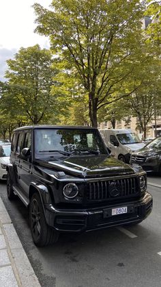 a black jeep is parked on the side of the road in front of some cars