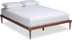 a bed with two pillows on top of it and a wooden foot board in the middle