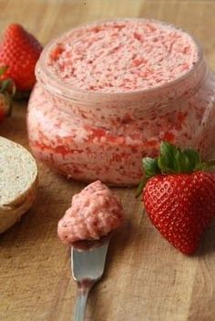 some strawberries and bread on a cutting board next to a jar of strawberry butter