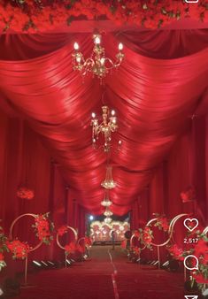 an aisle decorated with red flowers and chandelier