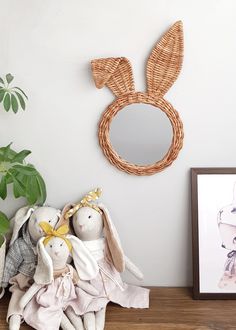 two stuffed animals sitting on top of a wooden table next to a mirror and potted plant