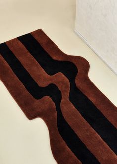 a brown and black rug on the floor with white walls in the back ground area