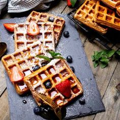 waffles with berries and ice cream on a slate platter next to other waffles