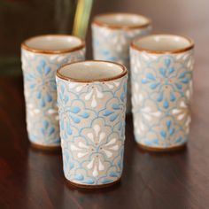 four blue and white cups sitting on top of a wooden table