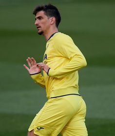 a man in yellow uniform holding a tennis racquet on top of a field