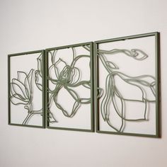 three pieces of metal art hanging on the wall