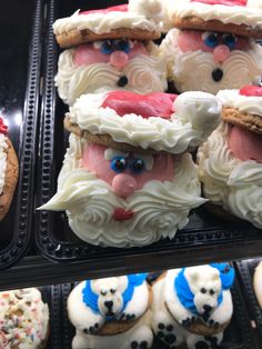 there are many decorated cookies in the trays on this shelf, including santa's face