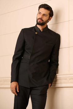 Black bandhgala in a premium suiting fabric featuring an overlapping front panel and novelty buttons, with a textured collar. Comes with a cotton-satin formal shirt and Jodhpuri trouser.
Components: 3
Pattern: Textured
Type Of Work: Linear Patterns
Neckline: Stand Collar
Sleeve Type: Straight Full
Fabric: Bandhgala : Suiting Fabric, Shirt : Cotton Satin, Trousers : Suiting Fabric
Color: Black
Other Details: 
Linear pattern textures
Overlapped panel
Novelty buttons
Occasion: 
Cocktail and Recepti Classic Fitted Sherwani With Naqshi Detailing, Classic Bandhgala For Eid Festivities, Classic Bandhgala For Eid Festival, Fitted Kurta With Zari Work For Semi-formal Occasions, Black Traditional Wear For Festive Semi-formal Occasions, Traditional Fitted Blazer With Zari Work, Designer Semi-formal Sets For Diwali, Fitted Traditional Blazer With Zari Work, Black Semi-formal Traditional Wear For Festive Occasions