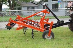 an orange tractor is parked in the grass