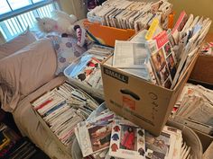 a pile of newspapers sitting on top of a bed next to a stuffed animal and window