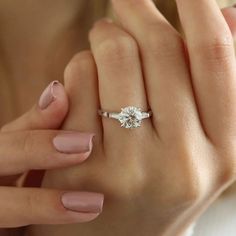 a woman's hand with a ring on it and her left hand holding an engagement ring