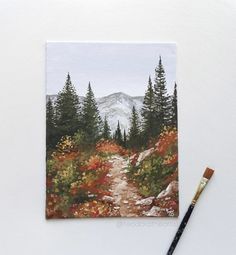 a painting of a path in the mountains with trees and flowers on it, next to a paintbrush