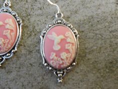 Beautiful cameo earrings!!!  Perfect gift!!!  Timeless classic look, both casual and formal!!  The cameo is set in a gorgeous tibetan silver setting, which measures about 1 1/2" x 1 1/4". The earring hooks are .925 stamped.  Quite a beautiful year round look!!!!  Thanks!!!  Lisa Silver Cameo Earrings As A Gift, Cameo Earrings, Earring Hooks, Pink Background, Timeless Classic, Classic Looks, Perfect Gift, Drop Earrings, Silver