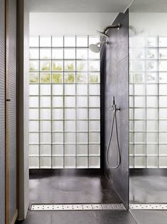 a bathroom with a walk in shower next to a glass block wall and tiled floor