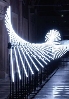 an artistic light sculpture in the middle of a walkway at night with white lights on it