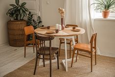 a table and chairs in a room with a potted plant on the window sill