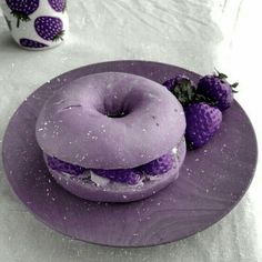 there is a purple doughnut and some strawberries on the plate