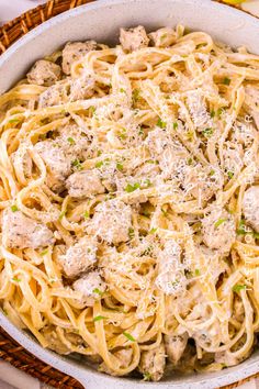 pasta with chicken and parmesan cheese in a white bowl on a wicker basket