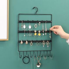 there is a rack with earrings hanging on it and a hand holding the hanger