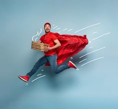 a man in a red shirt and blue jeans is running with a cardboard box on his back