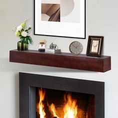 a fire place with a clock and pictures on the wall