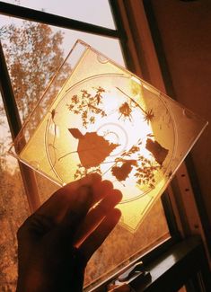 a person holding up a glass plate with leaves on it in front of a window