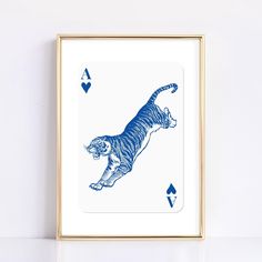 a blue tiger playing card in front of a gold frame on a white wall,