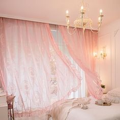 a bedroom with pink curtains and chandelier