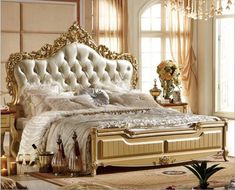 an ornate gold and white bed in a room with chandelier hanging from the ceiling