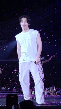 a male in a white shirt and pants on stage with confetti around him