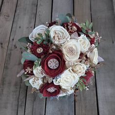 a bridal bouquet with red and white flowers on a wooden floor in front of wood planks