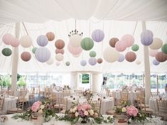 tables and chairs are set up in a tent with paper lanterns hanging from the ceiling